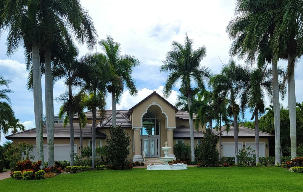 Stunning mansion exterior surrounded by palm trees, showcasing a tropical paradise setting.